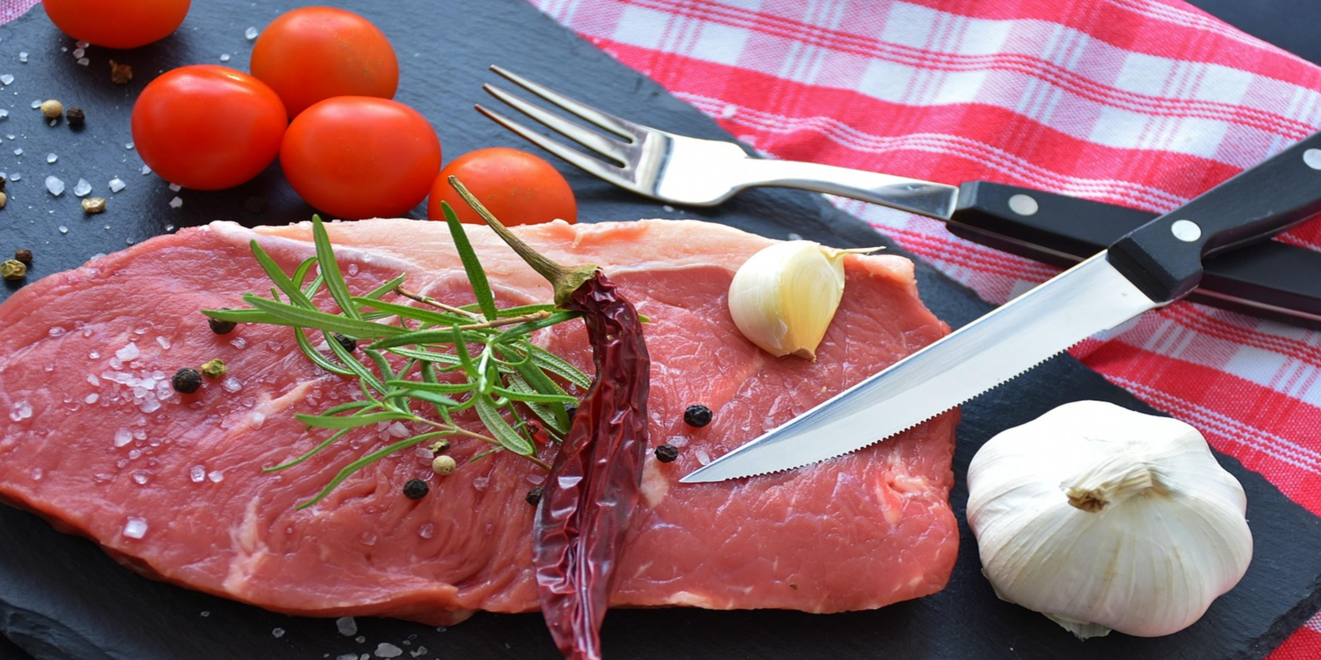 Un morceau de viande de bœuf assaisonné cru, avec un couteau appuyé dessus